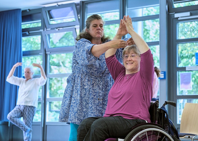 Hier tanzt eine Frau im Rollstuhl mit einer Frau im Stehen gemeinsam
